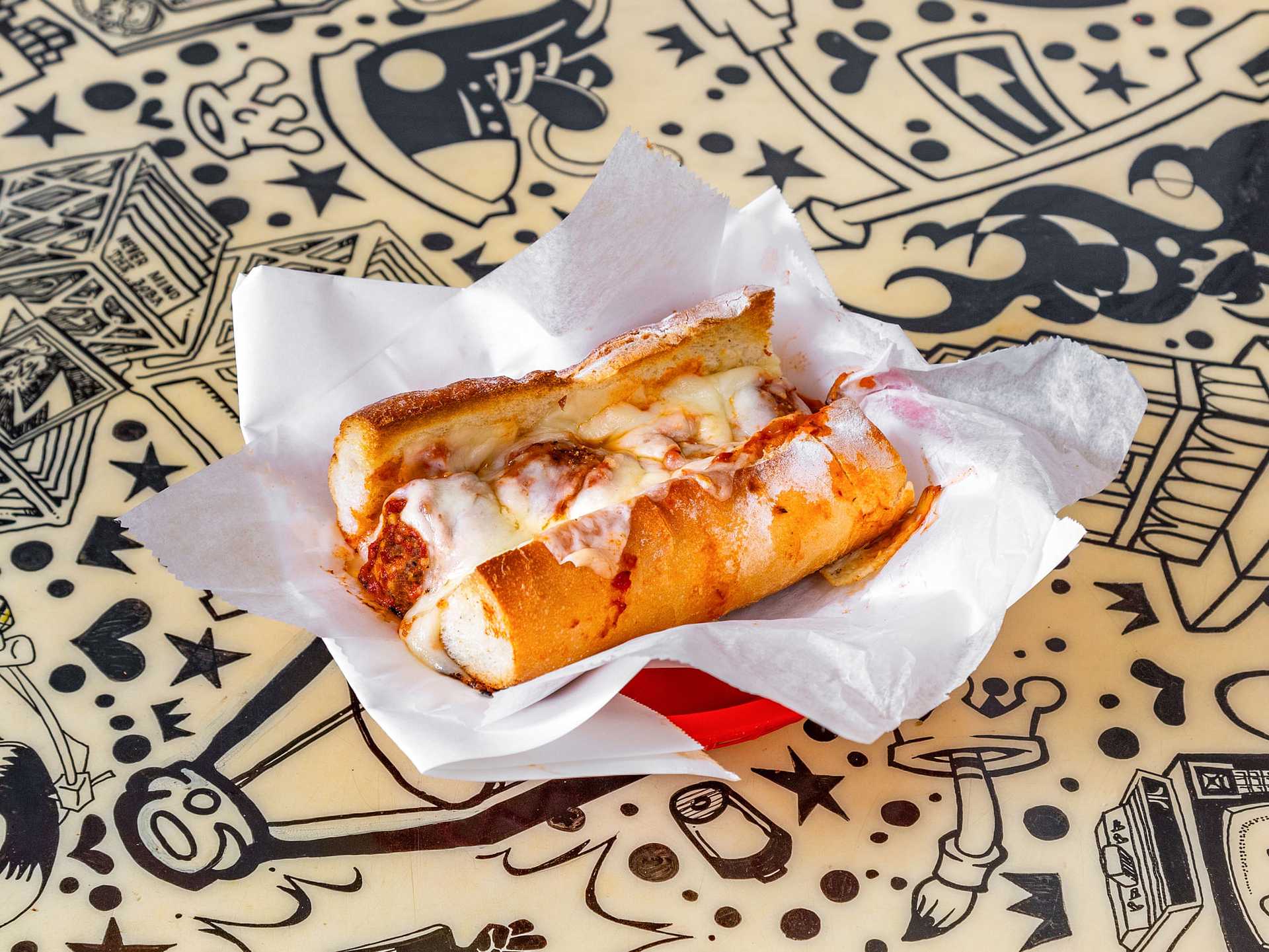 Meatball sub with melted cheese on a hoagie roll served on a decorated table.