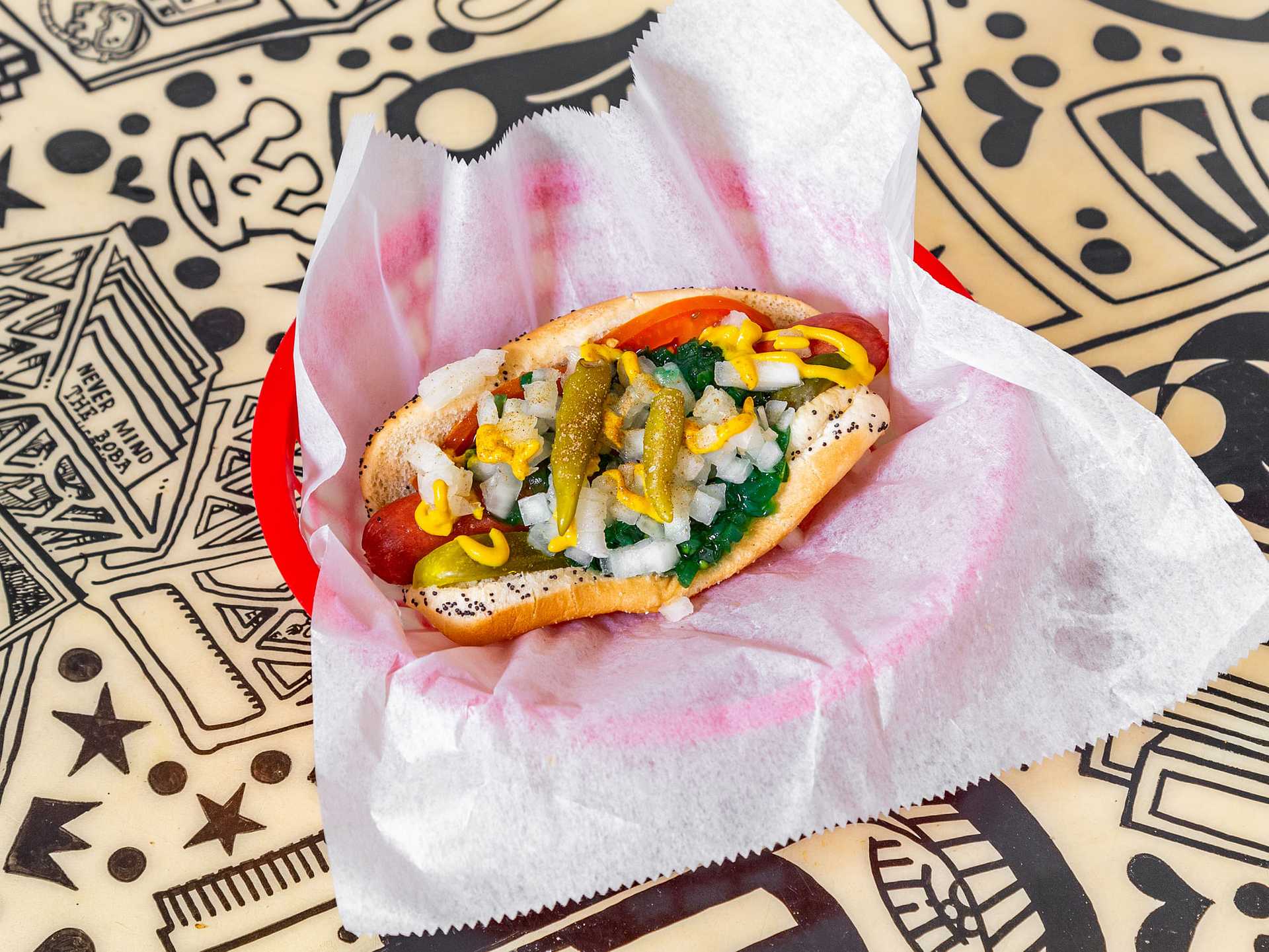 Chicago-style hot dog with mustard, relish, onions, tomato, pickle, and peppers on a poppy seed bun.